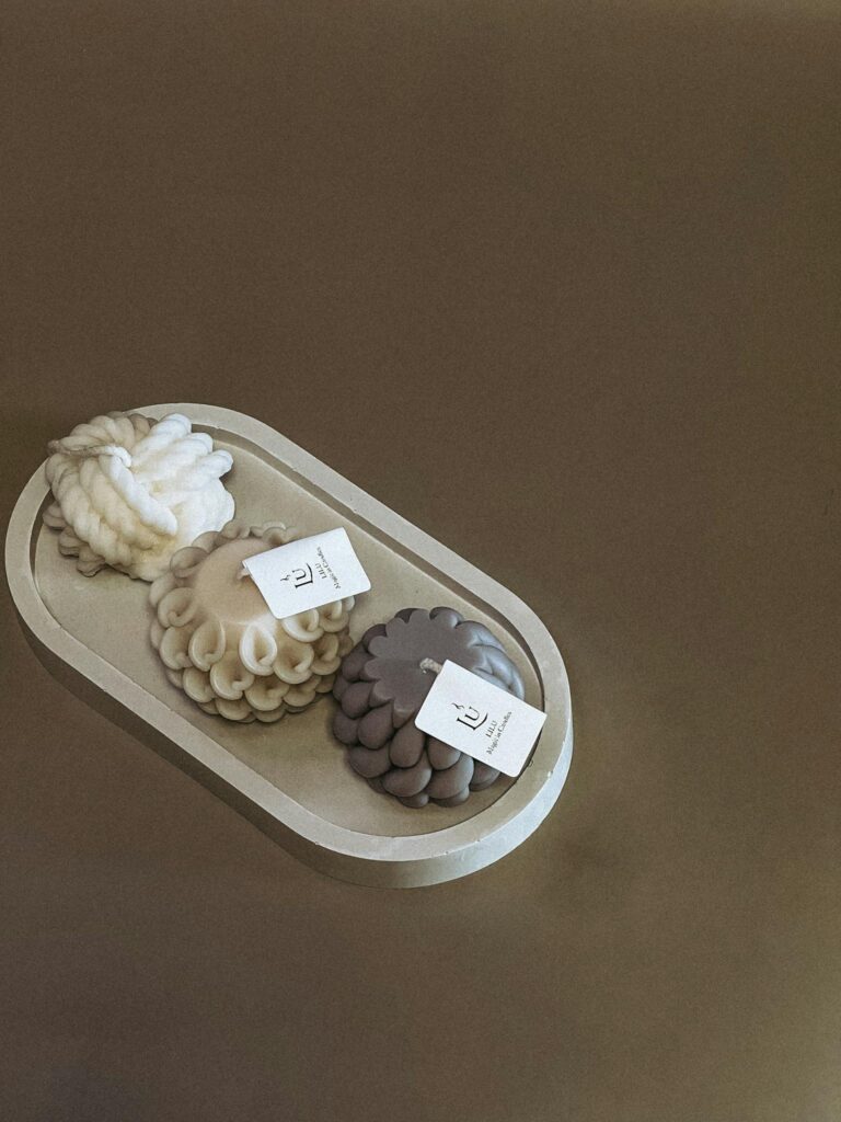 A stylish arrangement of uniquely shaped artisan candles on a decorative tray.