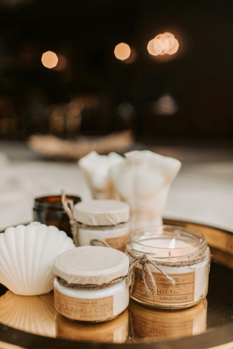 Warm, artisanal candles elegantly arranged in glass jars on a stylish round tray indoors.